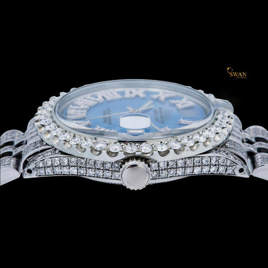 White iced-out watch with a blue mother-of-pearl dial, diamond-studded roman numerals, and a link band by swandiamond